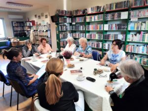 8 członkiń klubu książki przy stole podczas rozmowy o wrześniowej lekturze